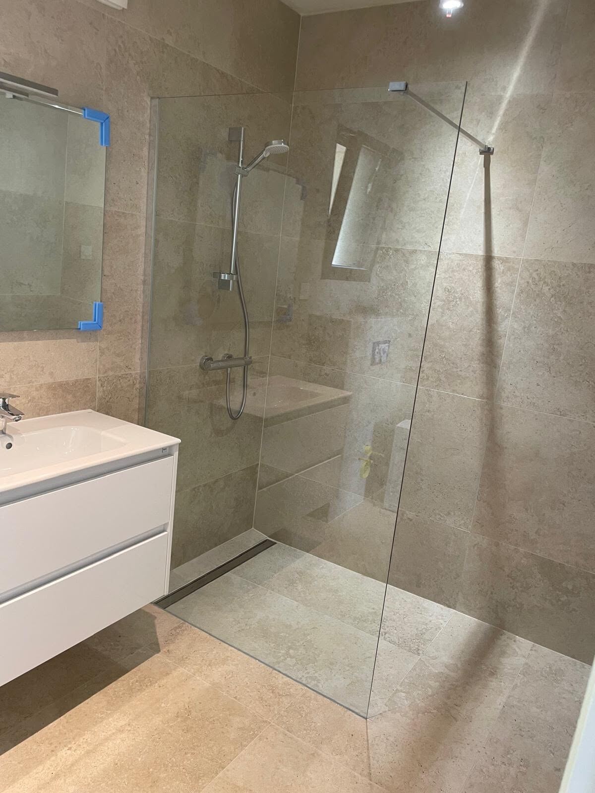 Douche à l'italienne en faïence effet pierre, paroi de verre