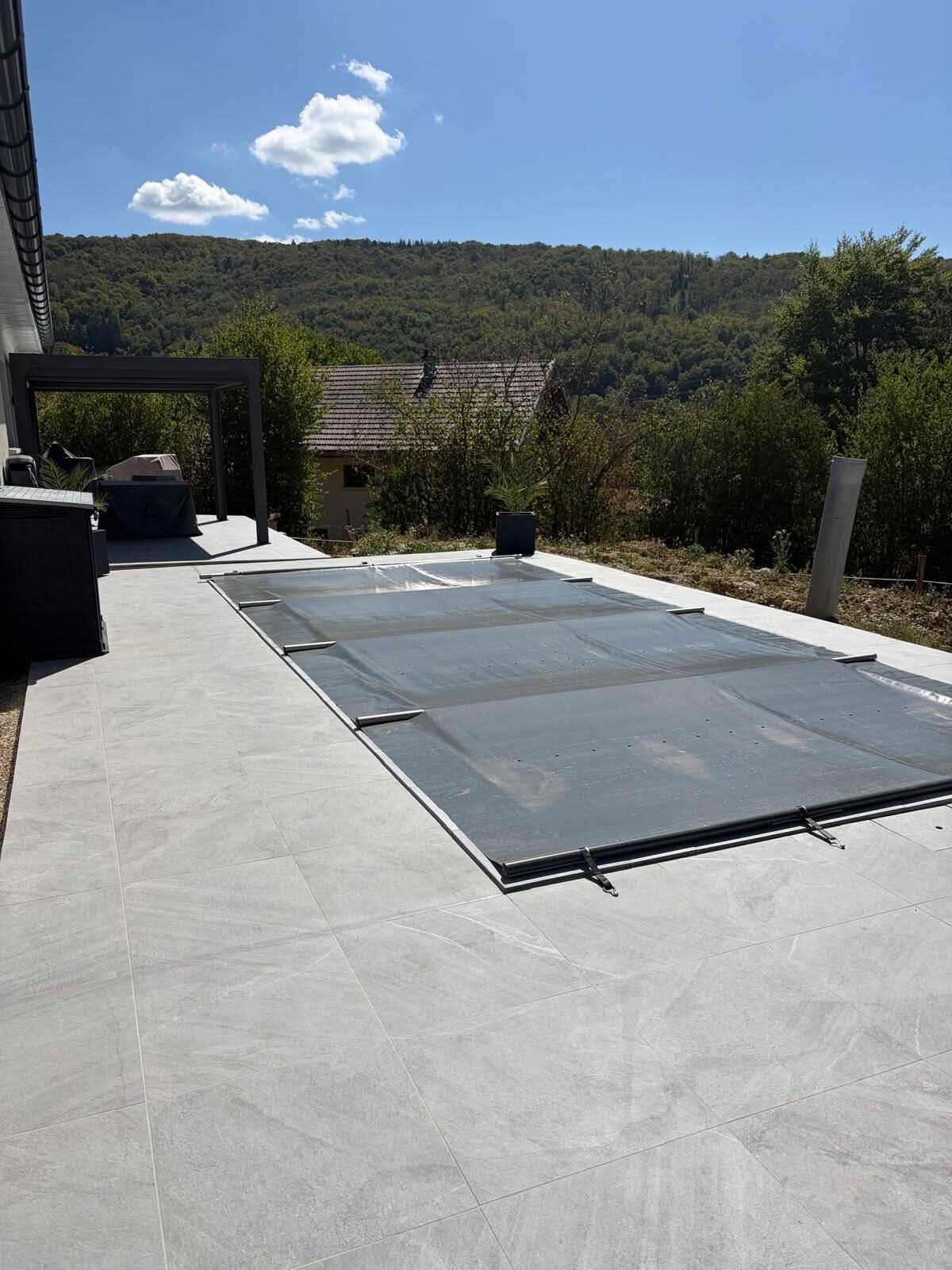 Terrasse en carrelage grand format gris avec margelles autour d'une piscine